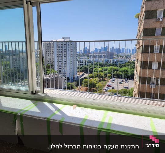חלון זכוכית עם מסגרת מתכת ונוף עירוני